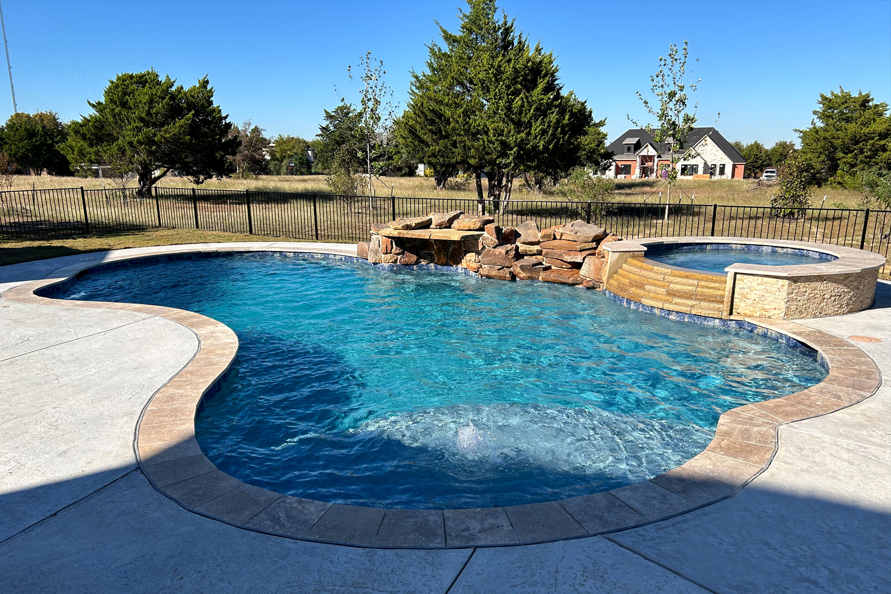 Freeform pool with rock waterfall and shaded seating
